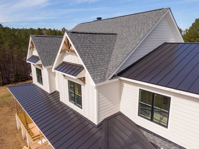 Roofing samples with different colors and reflectance labels displayed beside a sunlit residential roof.