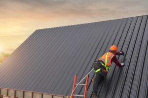Homeowner in safety gear examines roof shingles from a securely positioned ladder on a clear day.